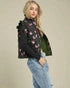 Woman wearing a black floral-patterned puffer vest on a beige background