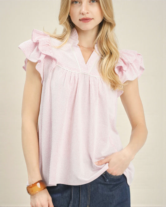 Woman wearing a pink ruffled blouse with a beige background