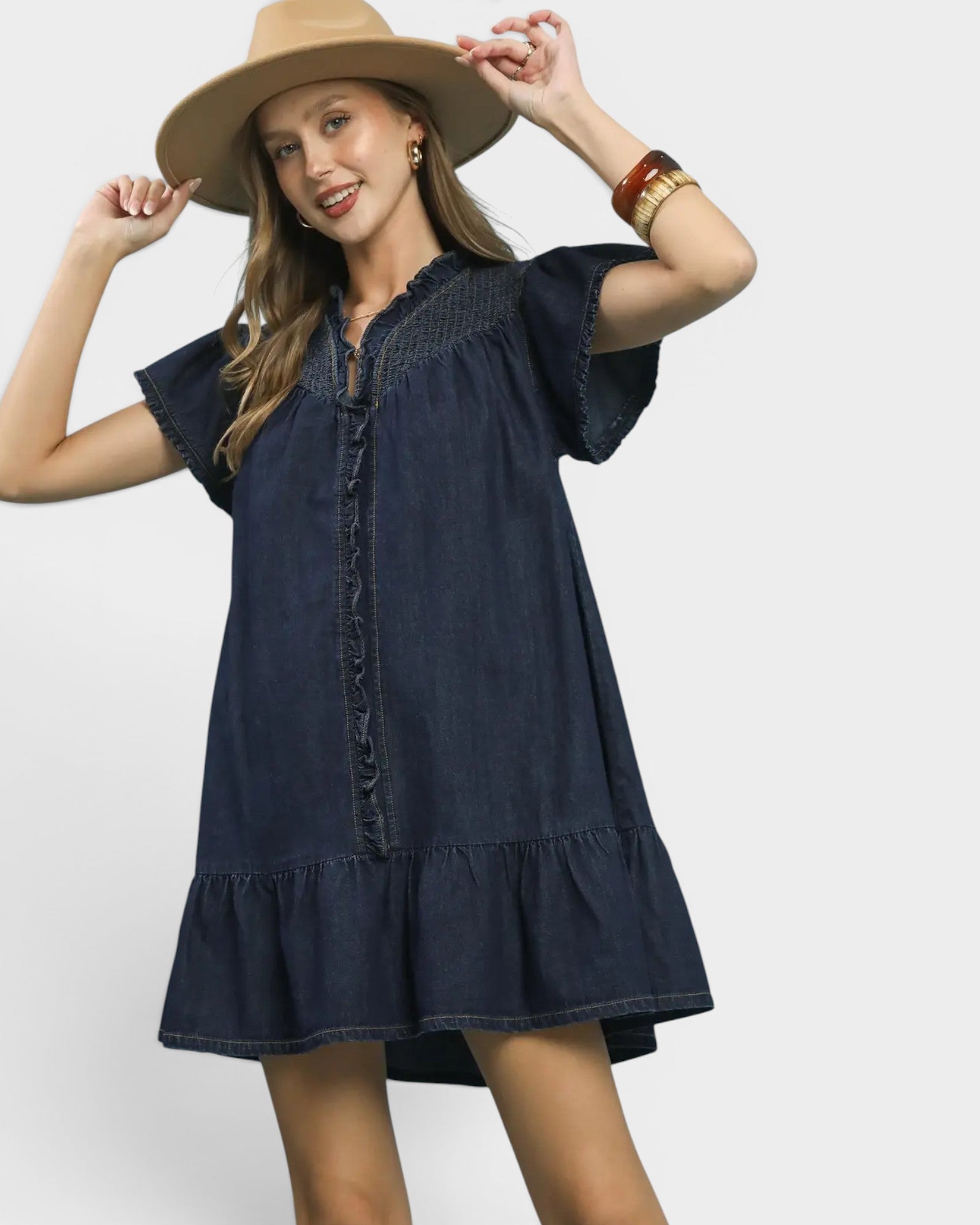 Woman wearing a navy blue dress and beige hat on a white background