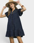 Woman wearing a navy blue dress and beige hat on a white background