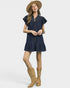 Woman wearing a navy dress, beige hat, and tan boots on a white background