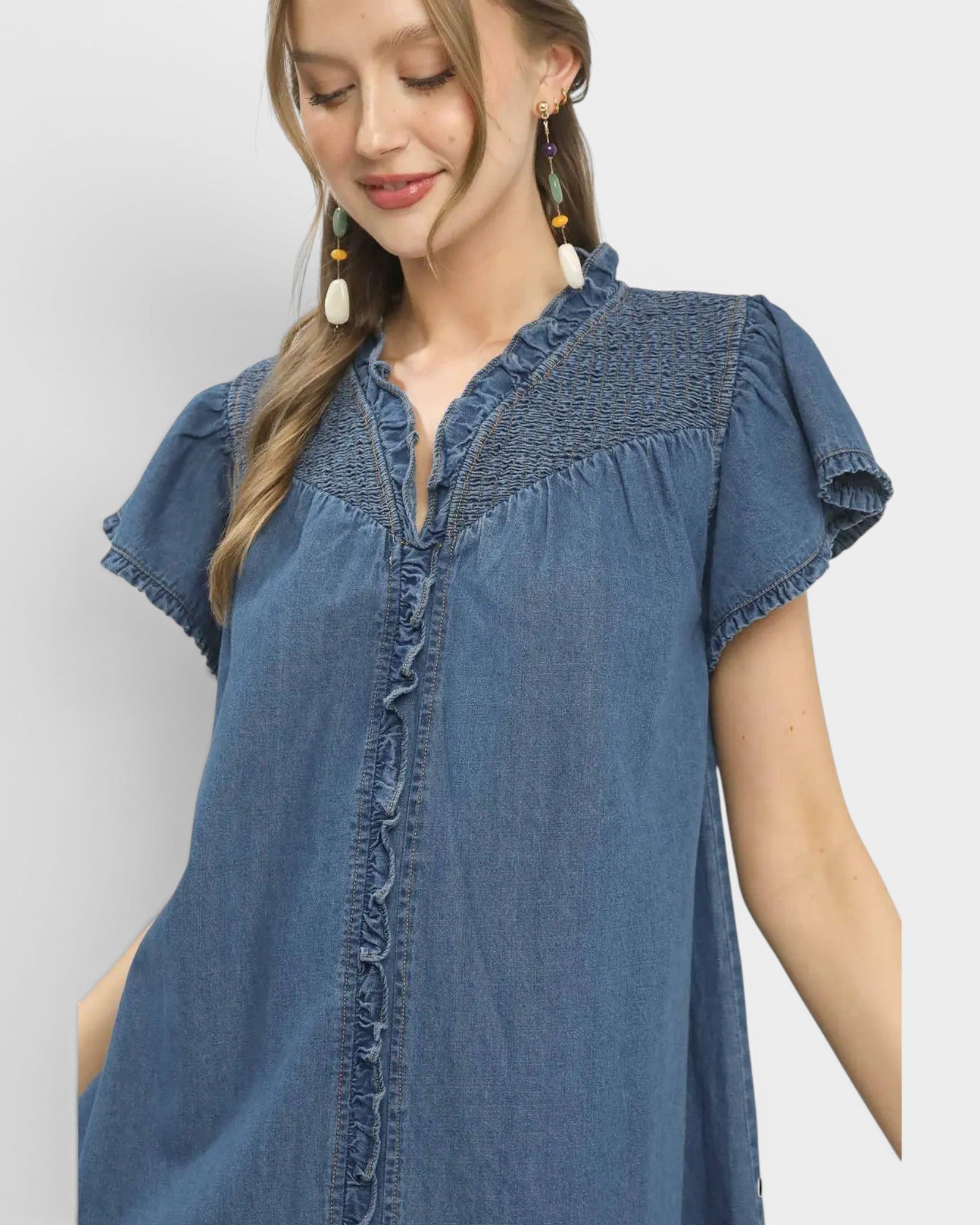 Woman wearing a blue denim dress with a plain background
