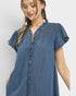 Woman wearing a blue denim dress with a plain background