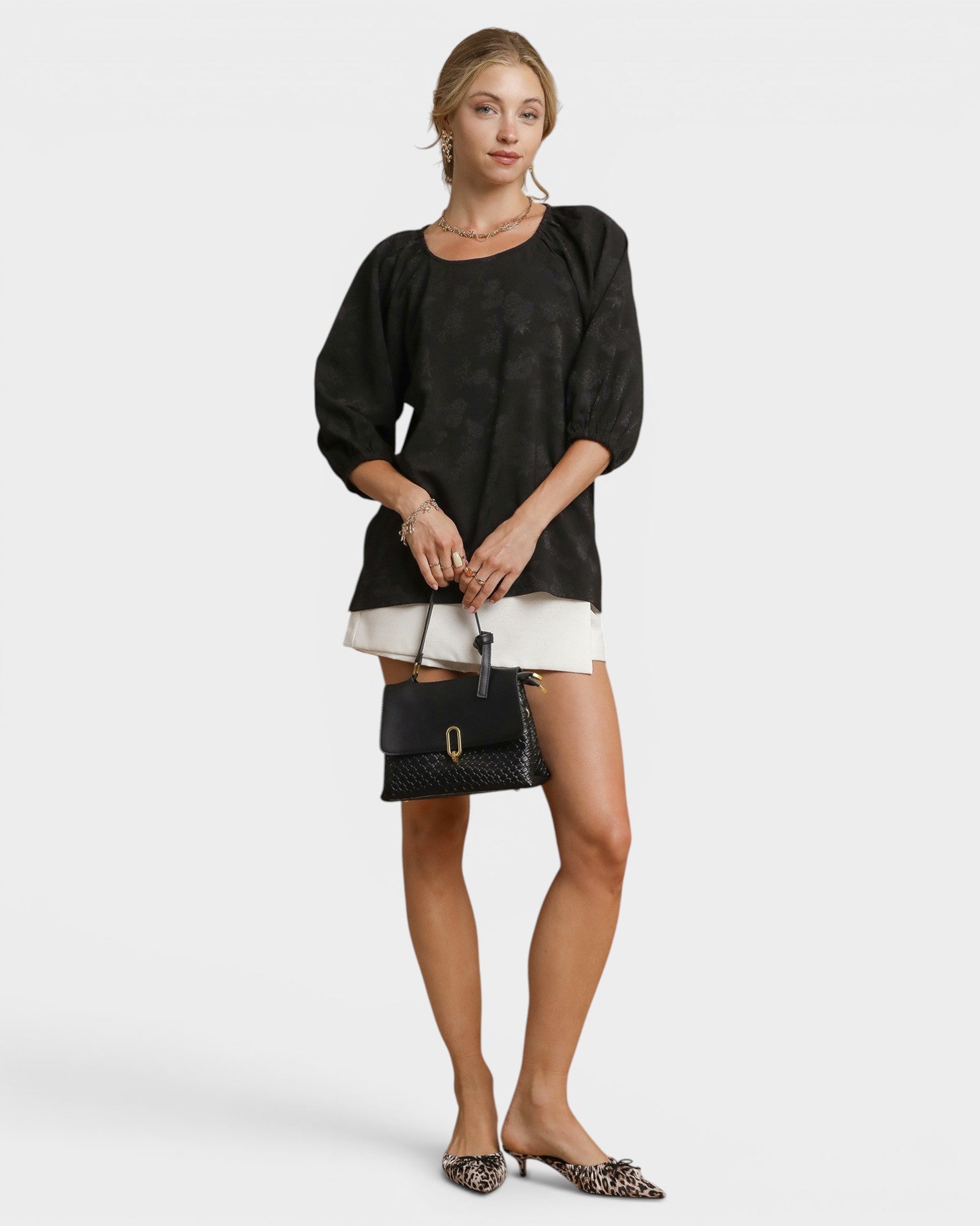 Woman holding a black handbag against a white background