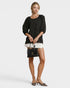 Woman holding a black handbag against a white background