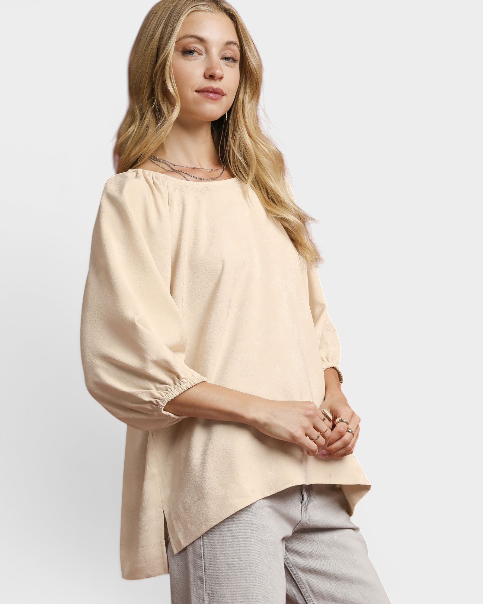 Woman wearing a beige blouse and light gray pants on a white background