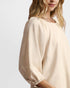 Woman wearing a beige blouse against a plain background