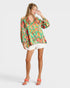 Woman wearing a colorful patterned blouse and white shorts on a white background