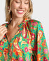 Woman wearing a colorful patterned top with a plain background