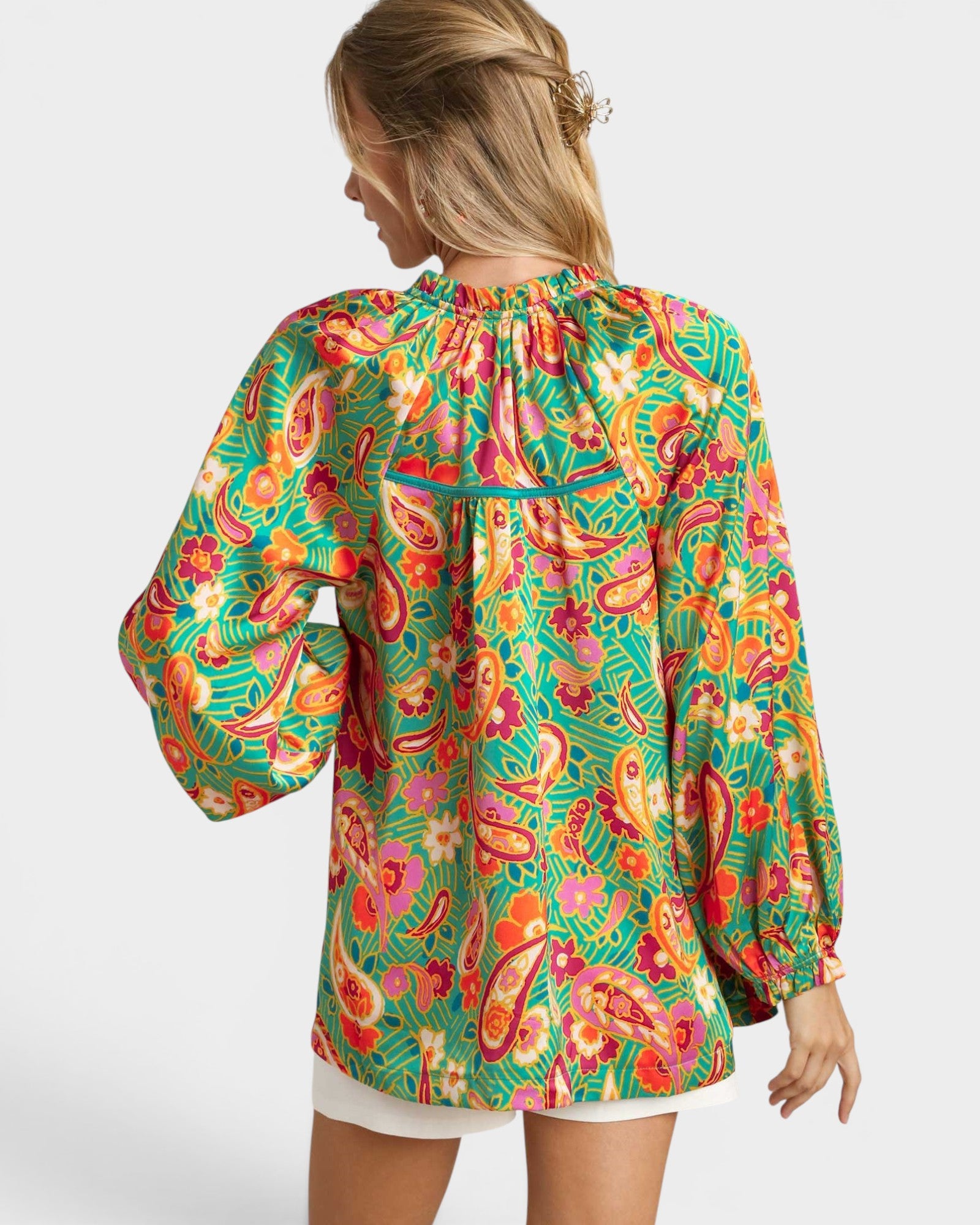 Woman wearing a colorful patterned blouse on a white background
