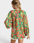 Woman wearing a colorful patterned blouse on a white background