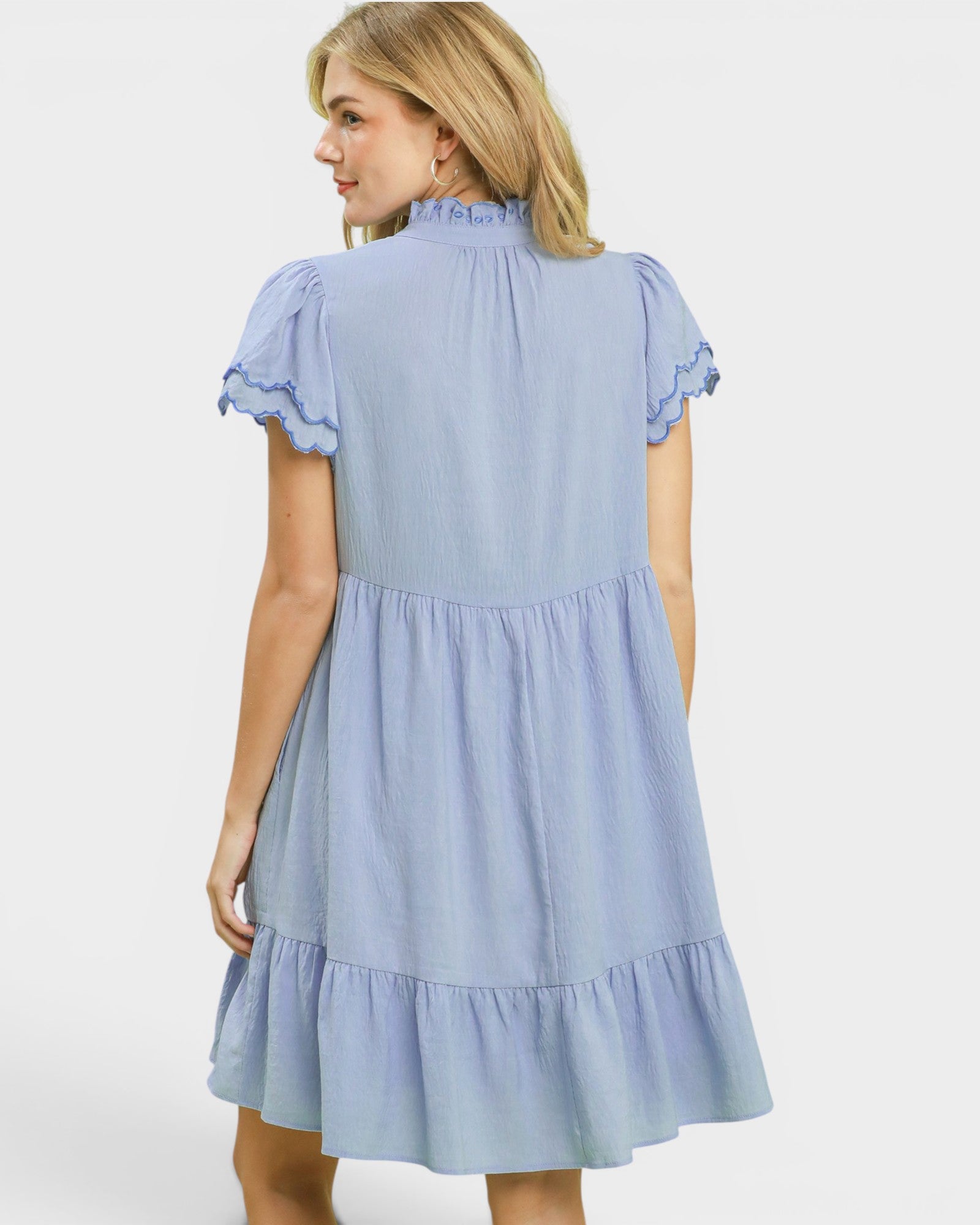 Woman wearing a light blue dress with lace trim on a white background