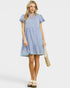 Woman wearing a light blue dress holding a beige bag on a white background