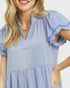 Woman wearing a light blue dress with ruffled sleeves on a plain background