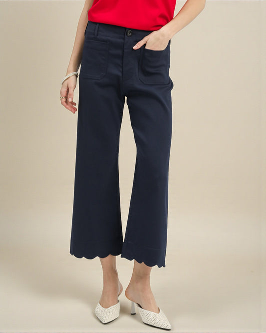 Person wearing navy blue wide-leg pants with a scalloped hem on a beige background