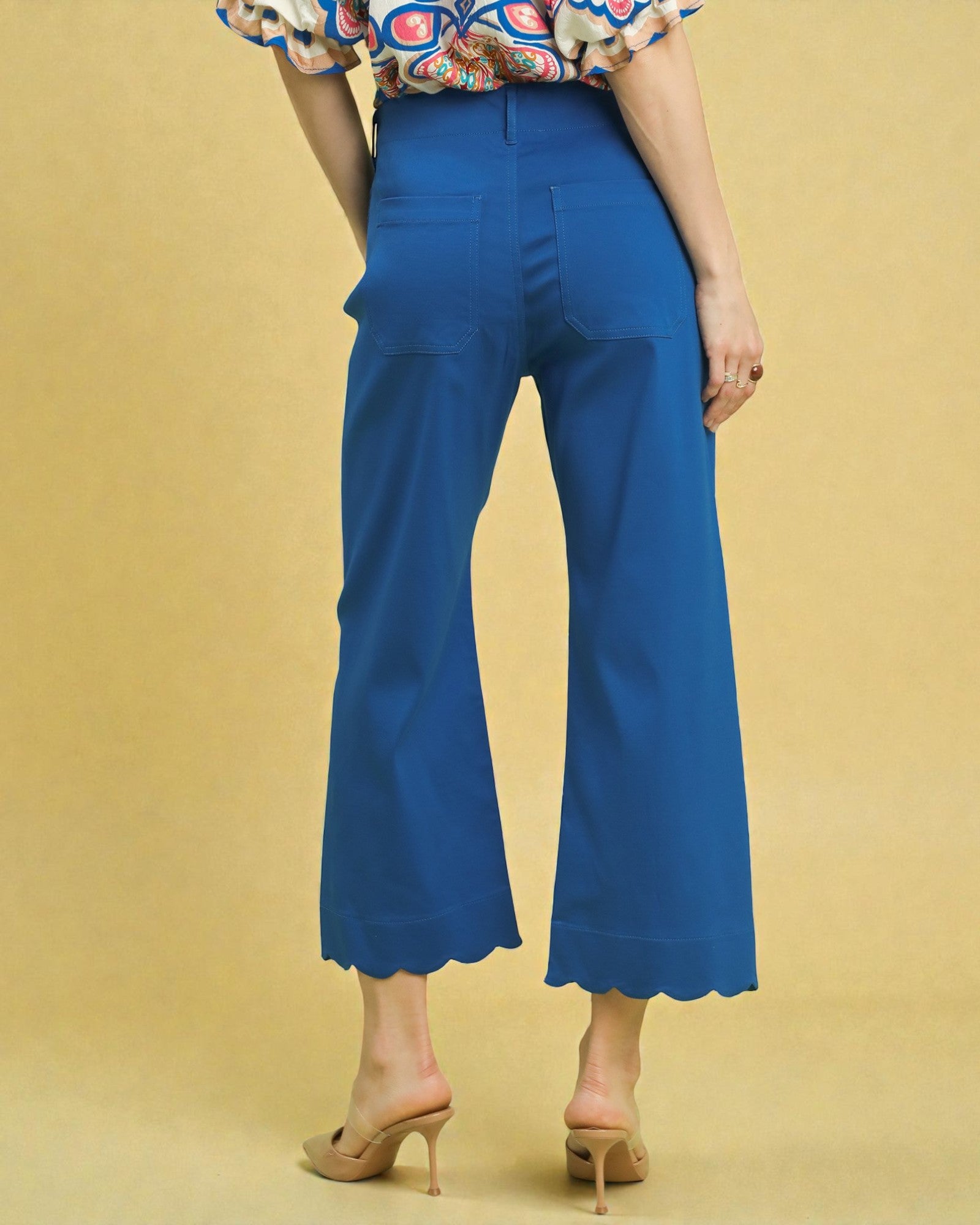 Person wearing blue flared pants on a beige background