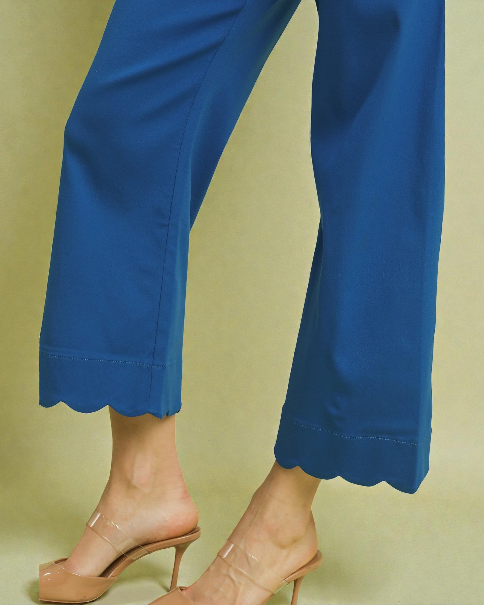 Blue pants with scalloped hem on a beige background
