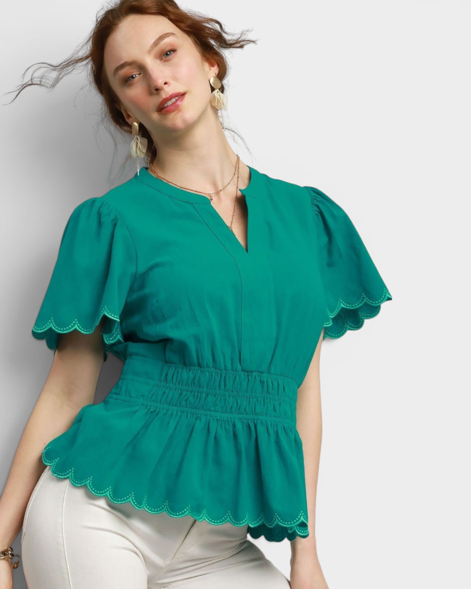 Woman wearing a green blouse with scalloped edges on a white background