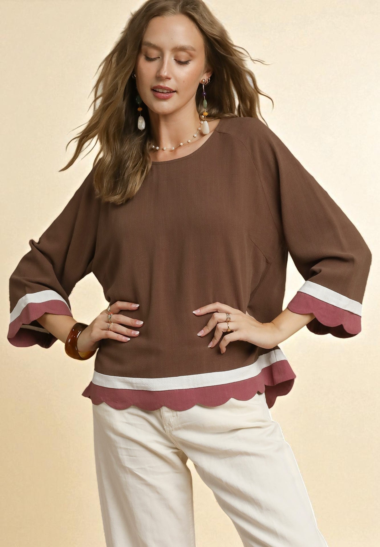 Woman wearing a brown blouse with white trim on a beige background