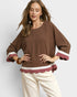 Woman wearing a brown blouse with maroon cuffs and trim on a white background