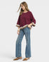 Woman wearing a burgundy sweater and blue jeans on a white background