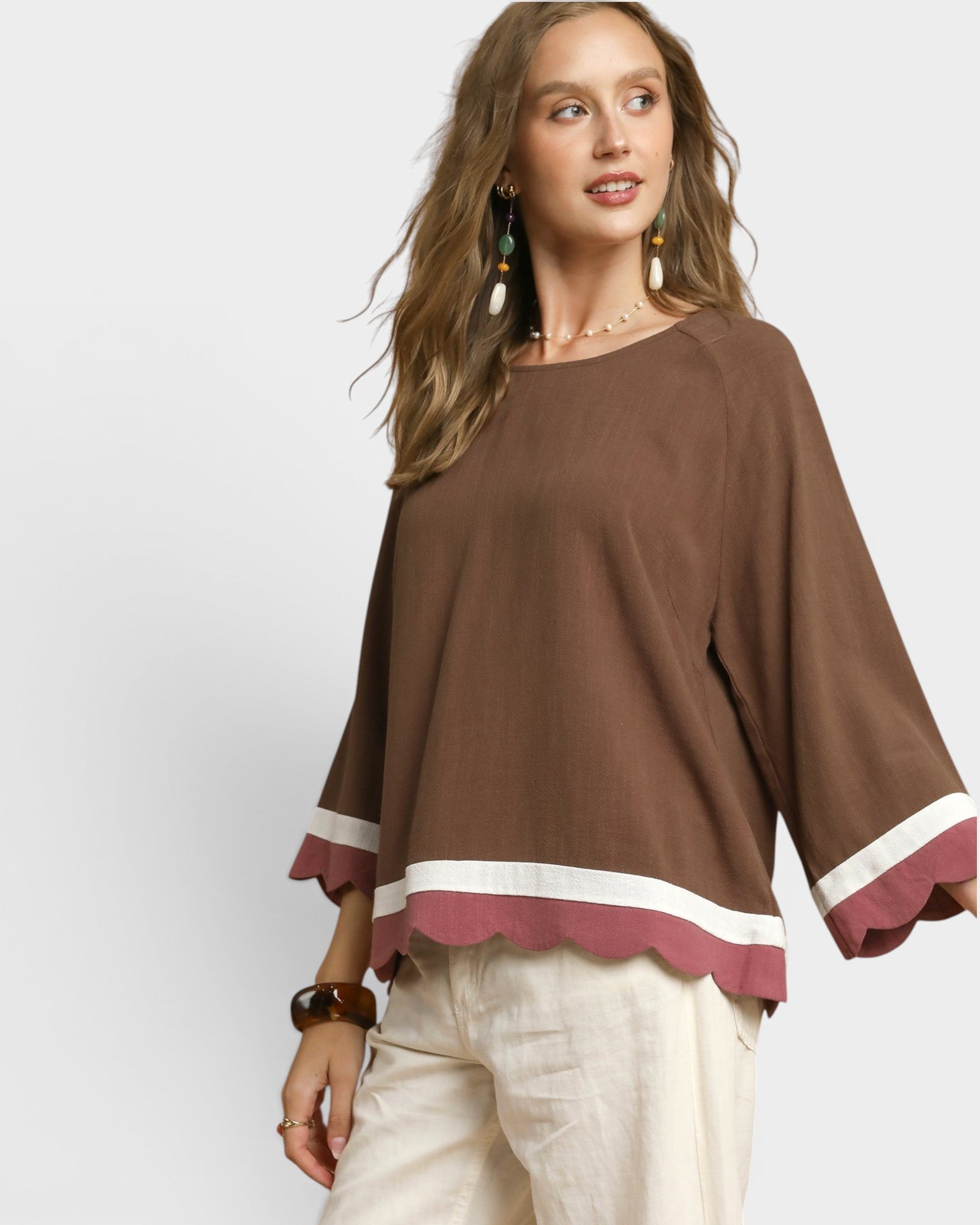 Woman wearing a brown blouse with white trim on a white background