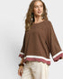 Woman wearing a brown blouse with white trim on a white background