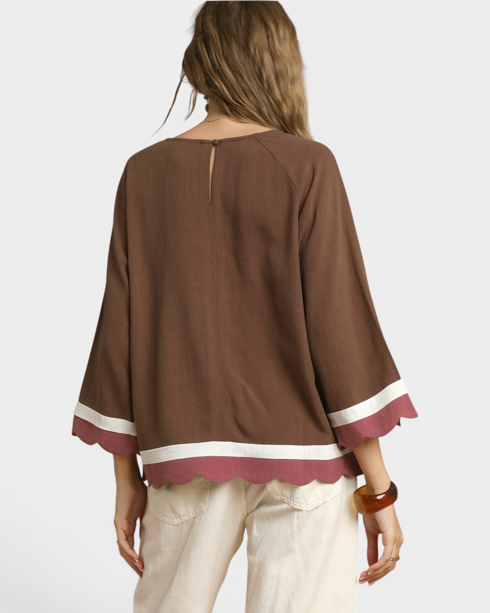 Brown blouse with white trim worn by a person on a plain background