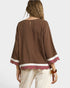 Brown blouse with white trim worn by a person on a plain background