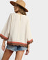 Woman wearing a beige top with red trim and denim shorts on a white background
