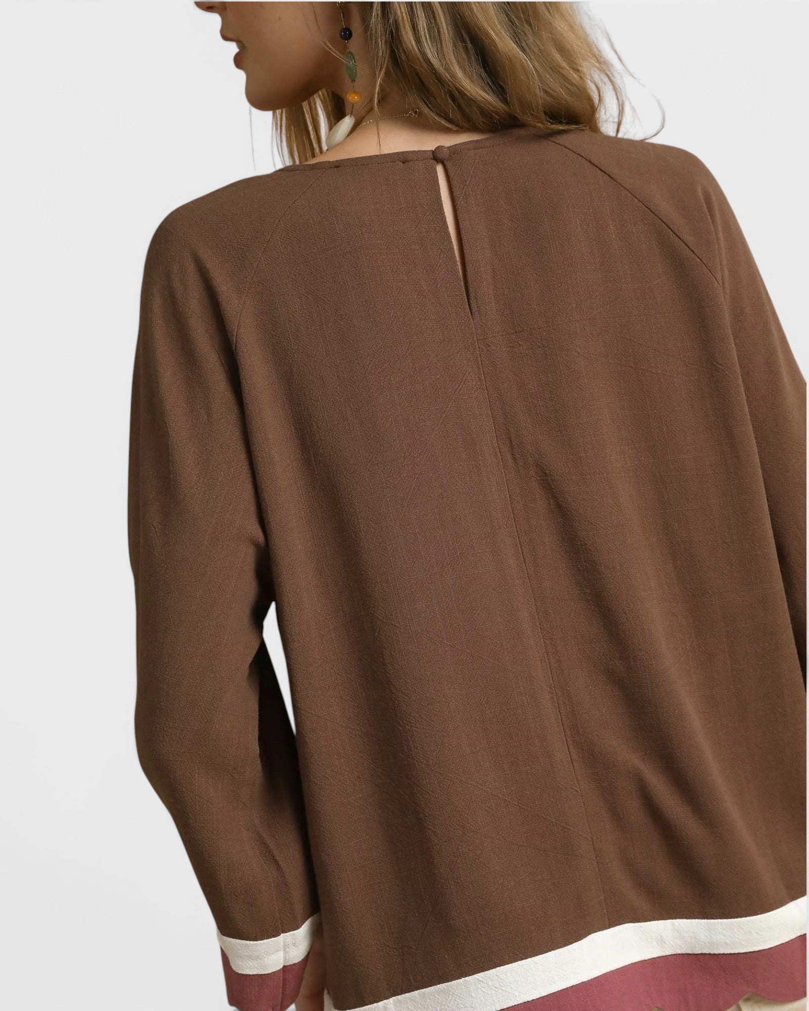 Brown long-sleeve top worn by a person on a light gray background