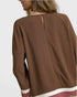 Brown long-sleeve top worn by a person on a light gray background