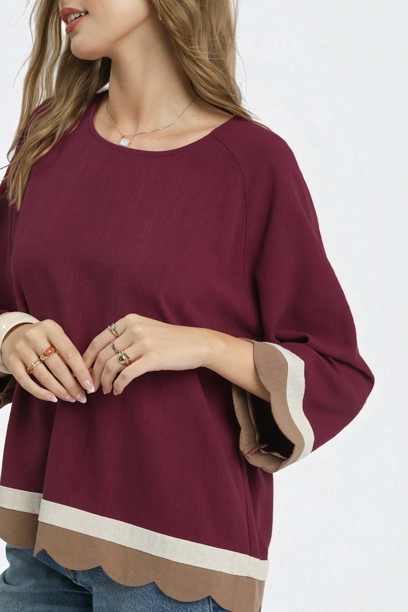 Maroon top with scalloped hem and cuffs on a white background