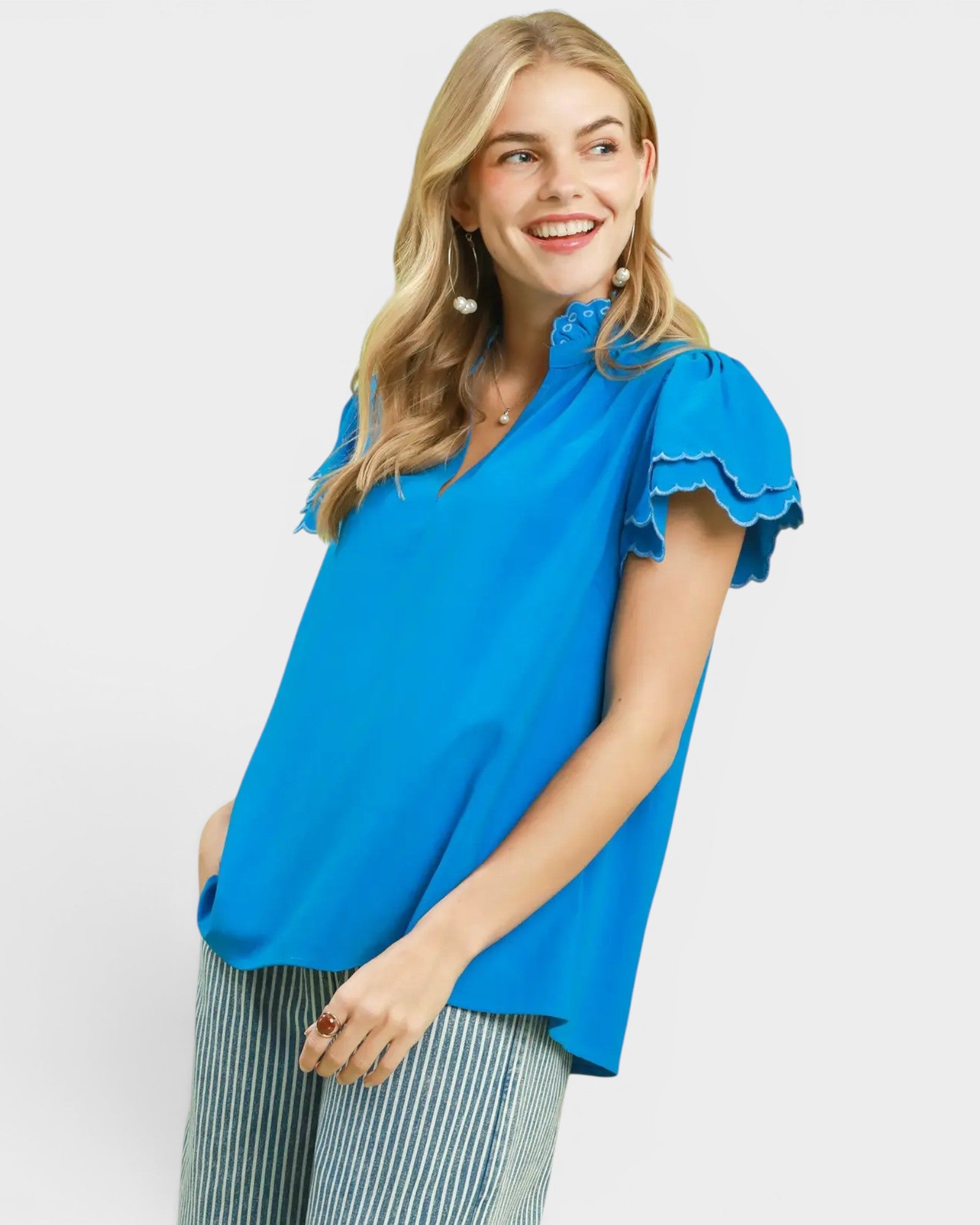 Woman wearing a blue blouse with ruffled sleeves on a white background