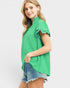 Woman wearing a green blouse with ruffled sleeves and denim shorts on a white background