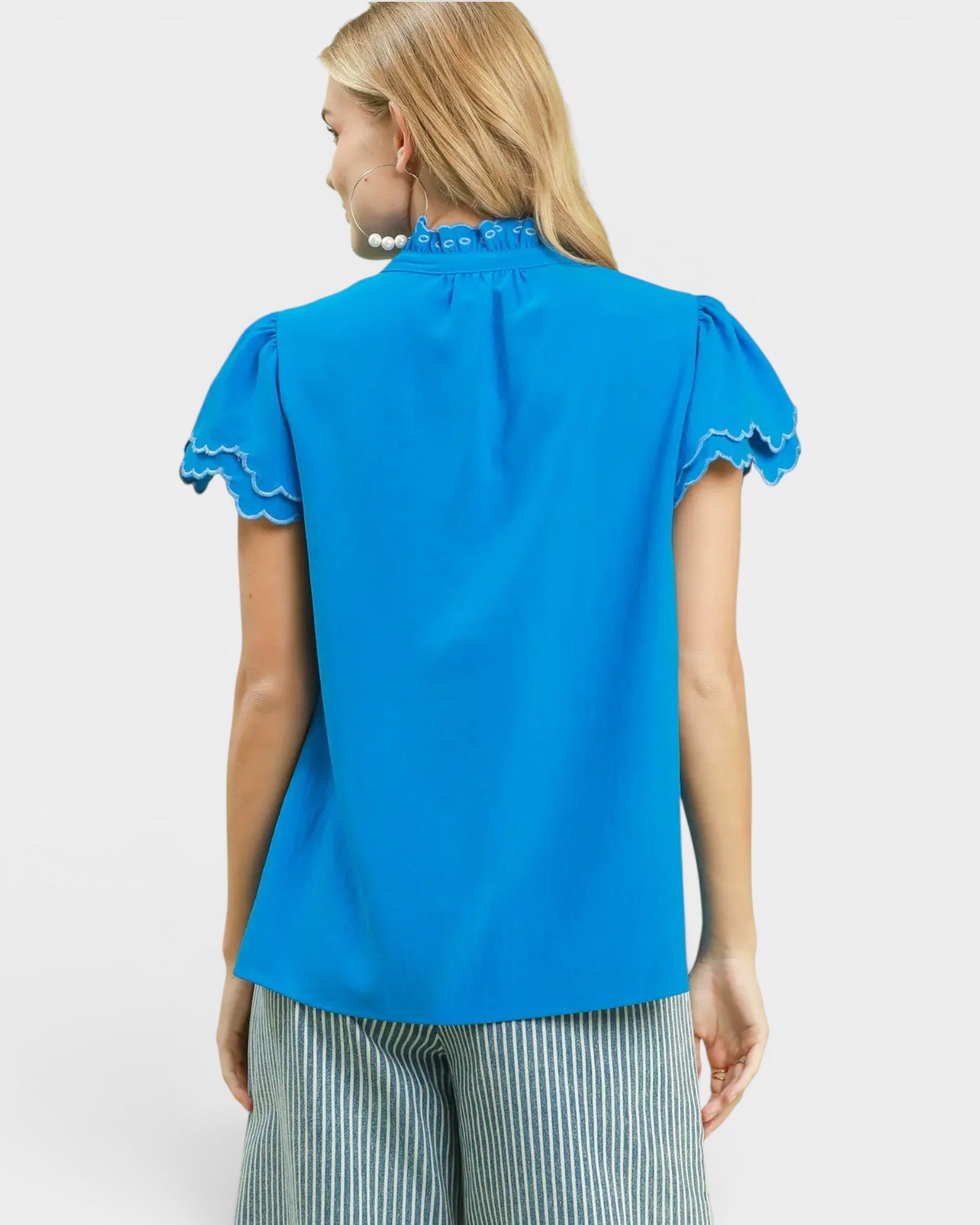 Woman wearing a blue blouse with ruffled sleeves on a white background