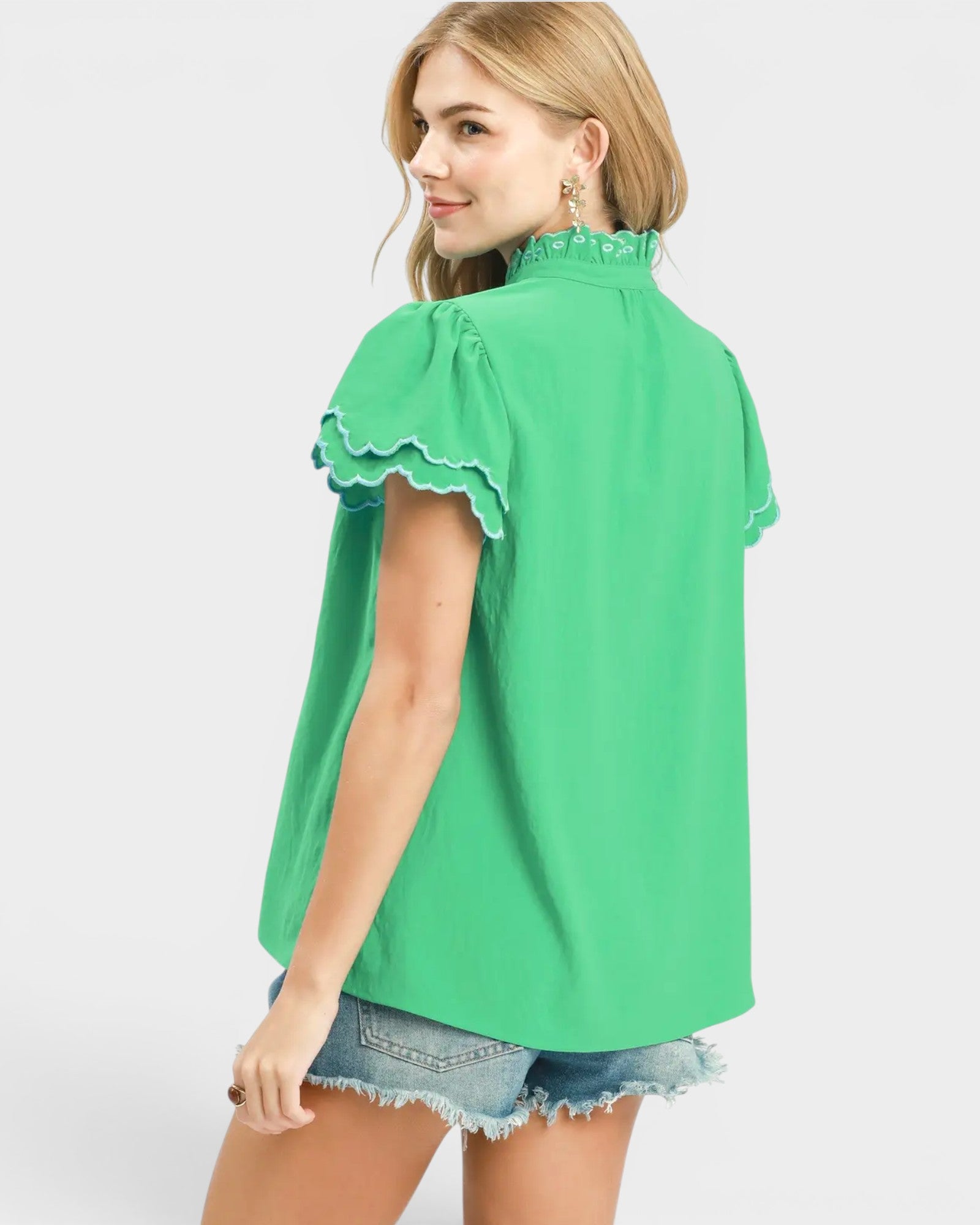 Woman wearing a green blouse with ruffled details on a white background