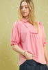 Woman wearing a pink blouse with puffed sleeves against a light green background