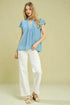 Woman wearing a light blue blouse and white pants on a beige background
