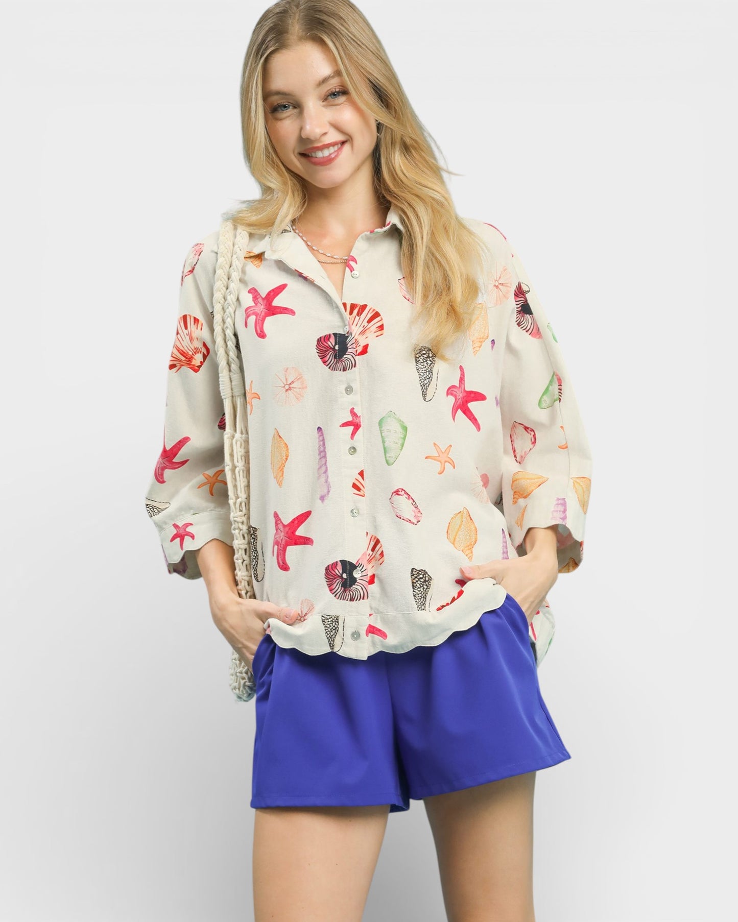 Woman wearing a colorful patterned shirt and blue shorts on a white background
