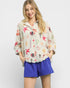 Woman wearing a colorful patterned shirt and blue shorts on a white background