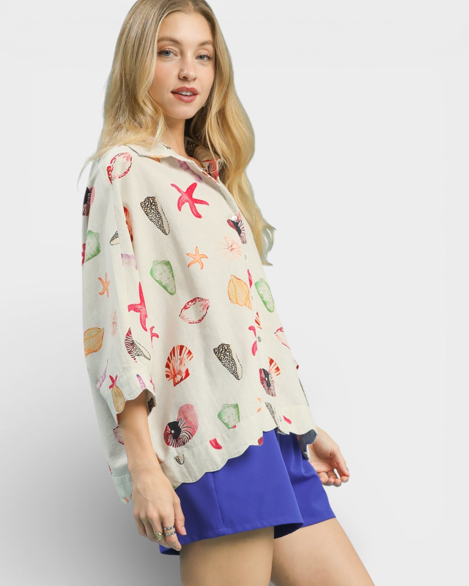 Woman wearing a colorful shell-patterned blouse with a plain background