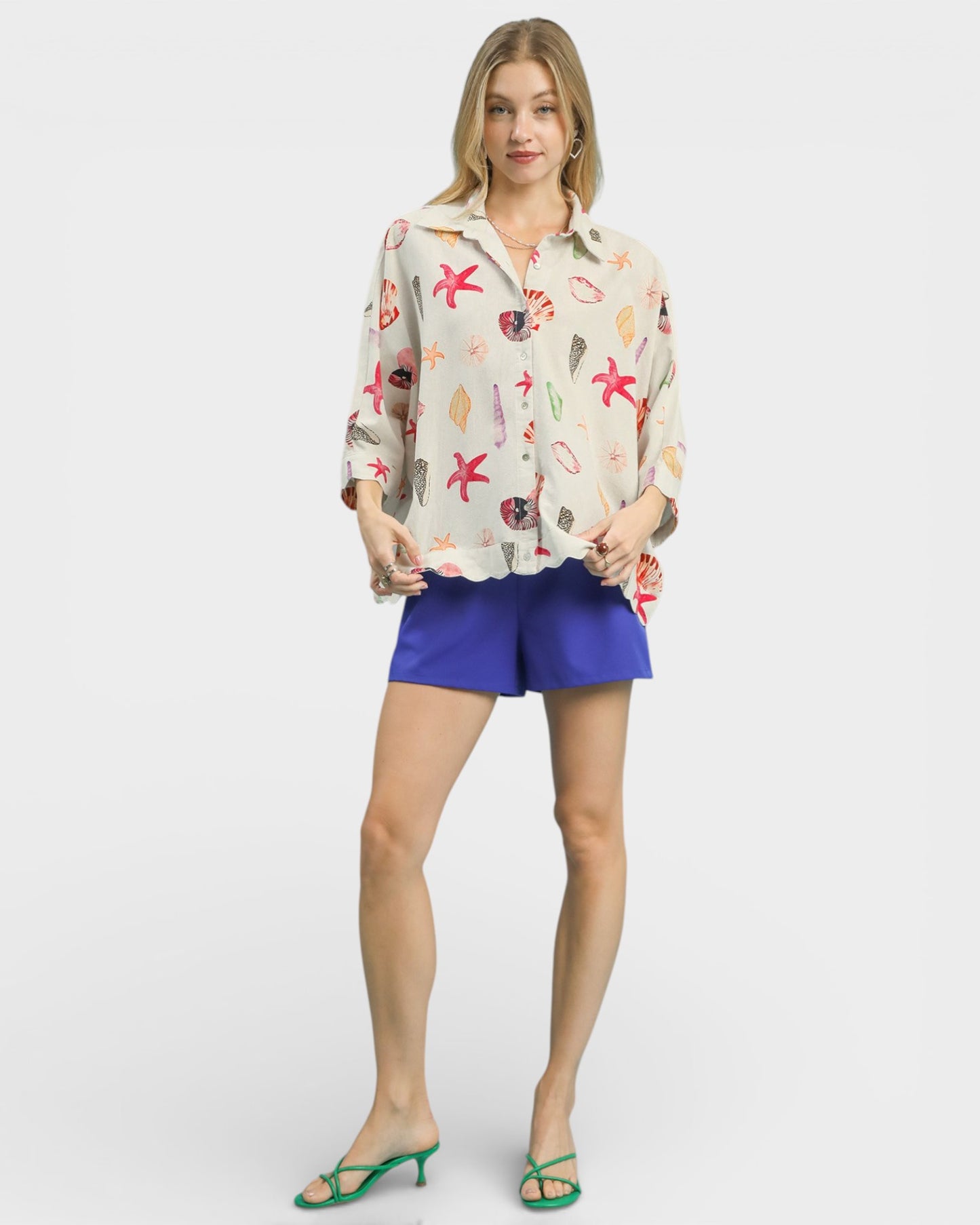 Woman wearing a floral blouse and blue shorts on a white background
