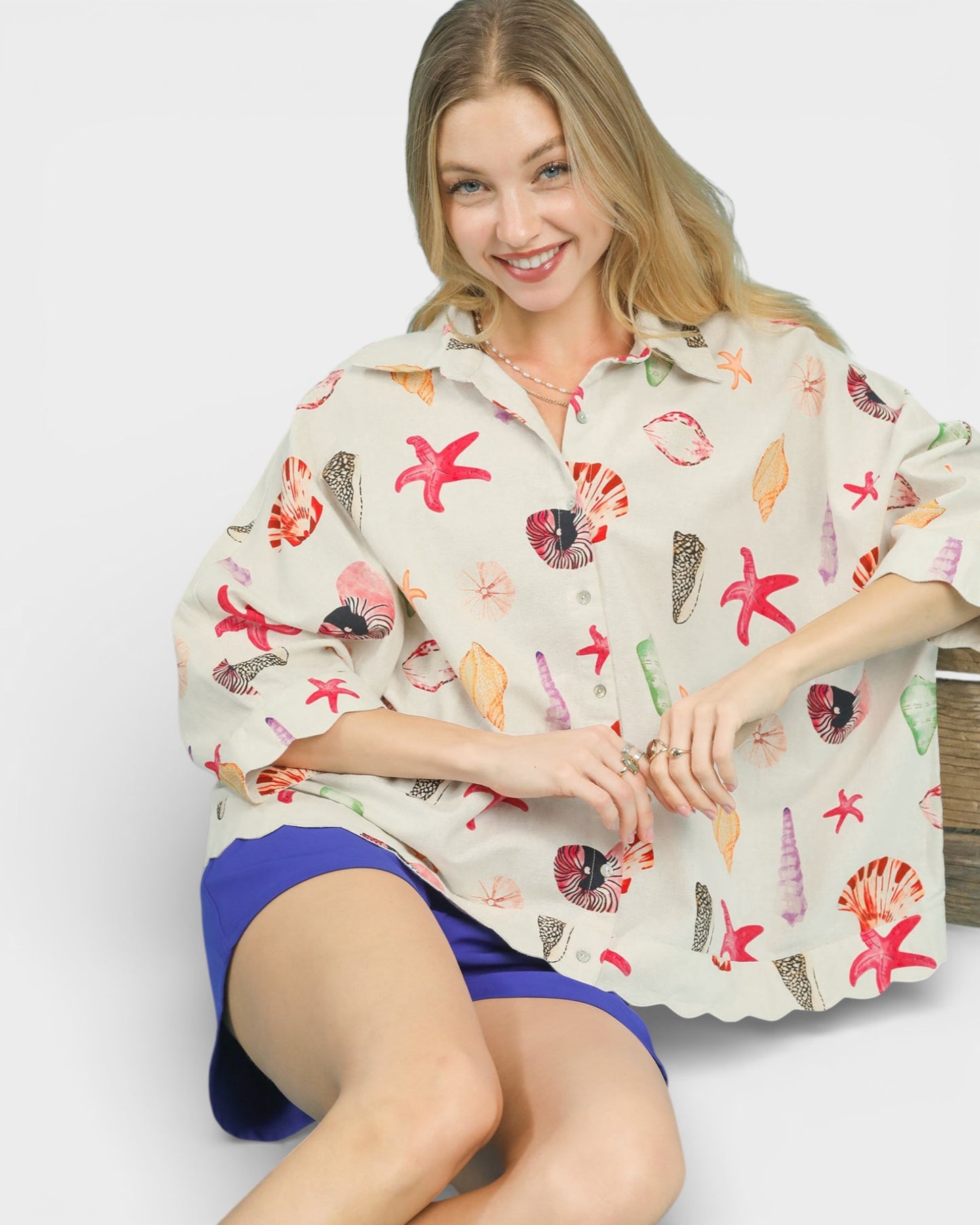Woman wearing a colorful shell-patterned shirt on a plain background
