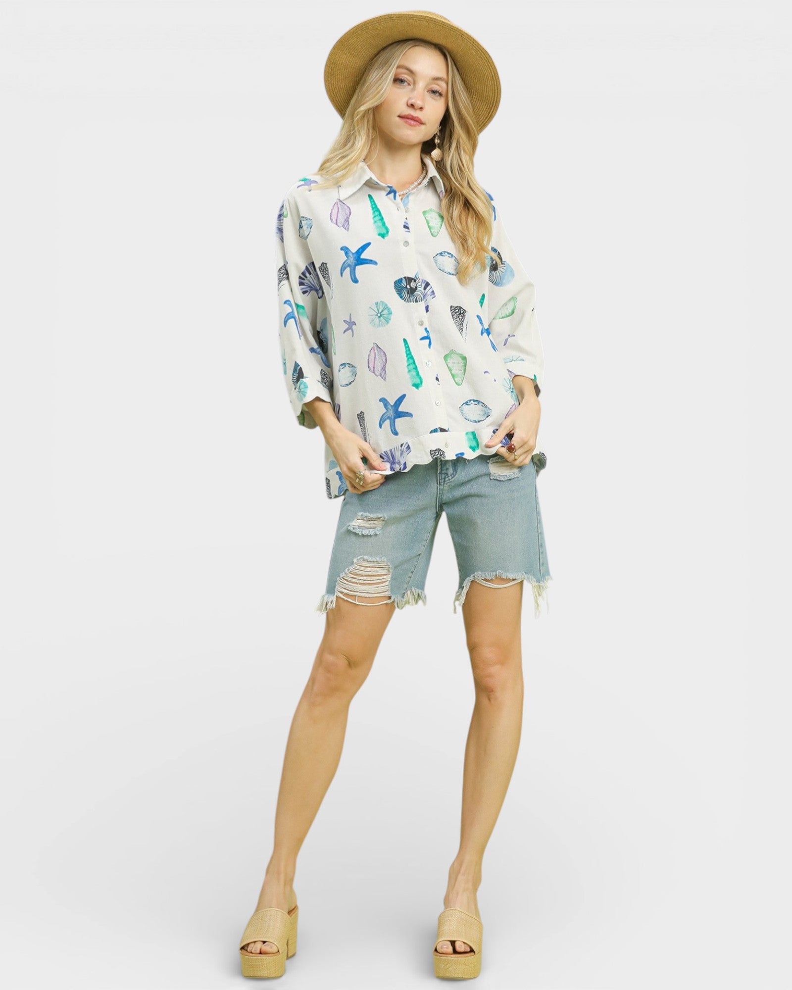 Woman wearing a patterned shirt and denim shorts on a white background