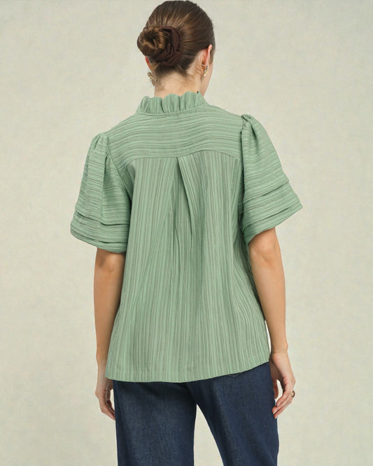 Person wearing a green striped blouse with short sleeves on a plain background