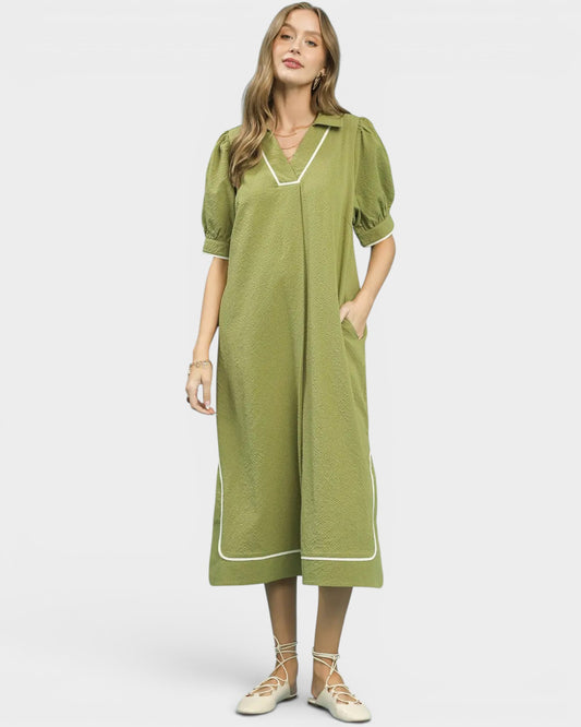 Woman wearing a green dress with white trim on a white background