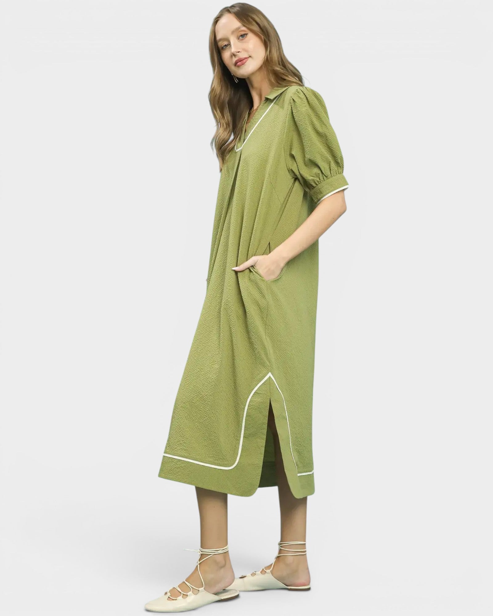 Woman wearing a green dress with white trim on a white background