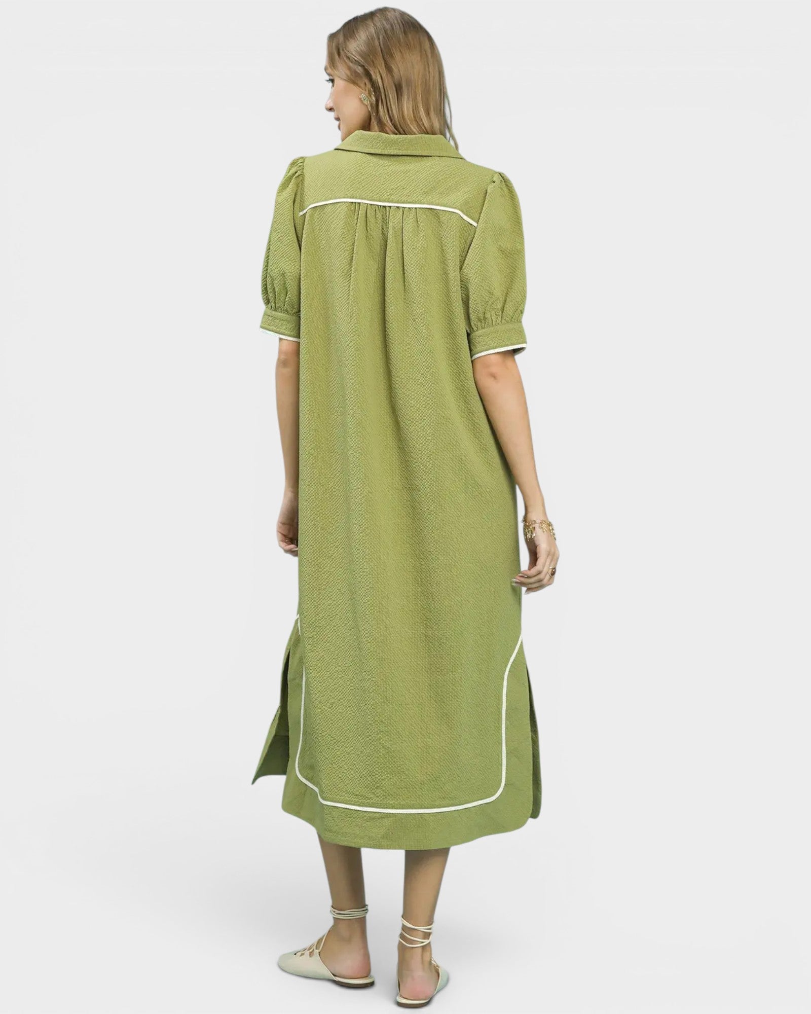 Woman wearing a green dress with white trim on a white background