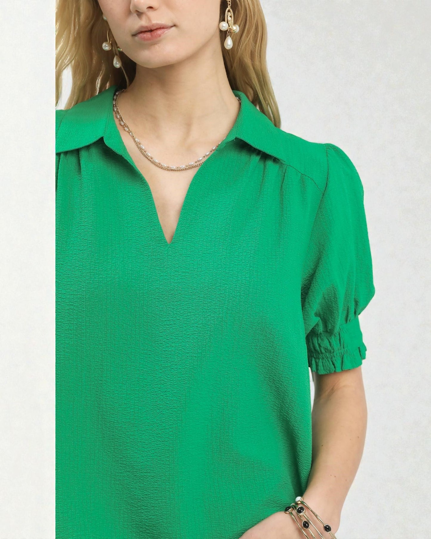 Green blouse worn by a person on a white background